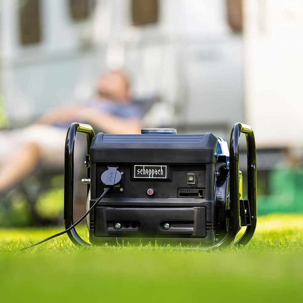 Ein Scheppach Notstromgenerator steht auf einer Wieser vor einem Campingwagen