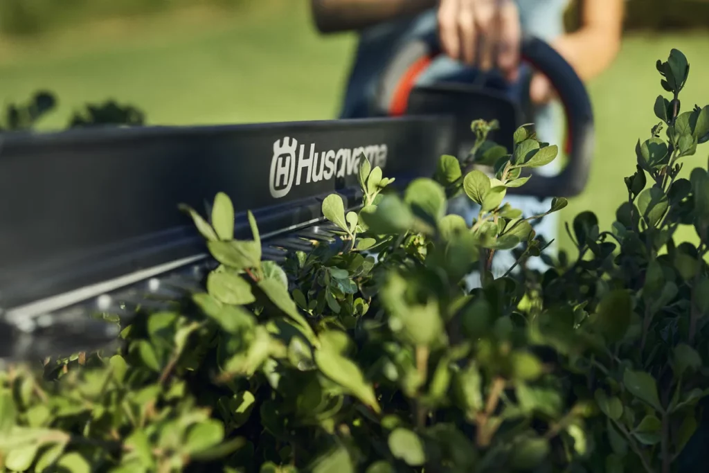 Husqvarna Akku Heckenschere schneidet eine Hecke