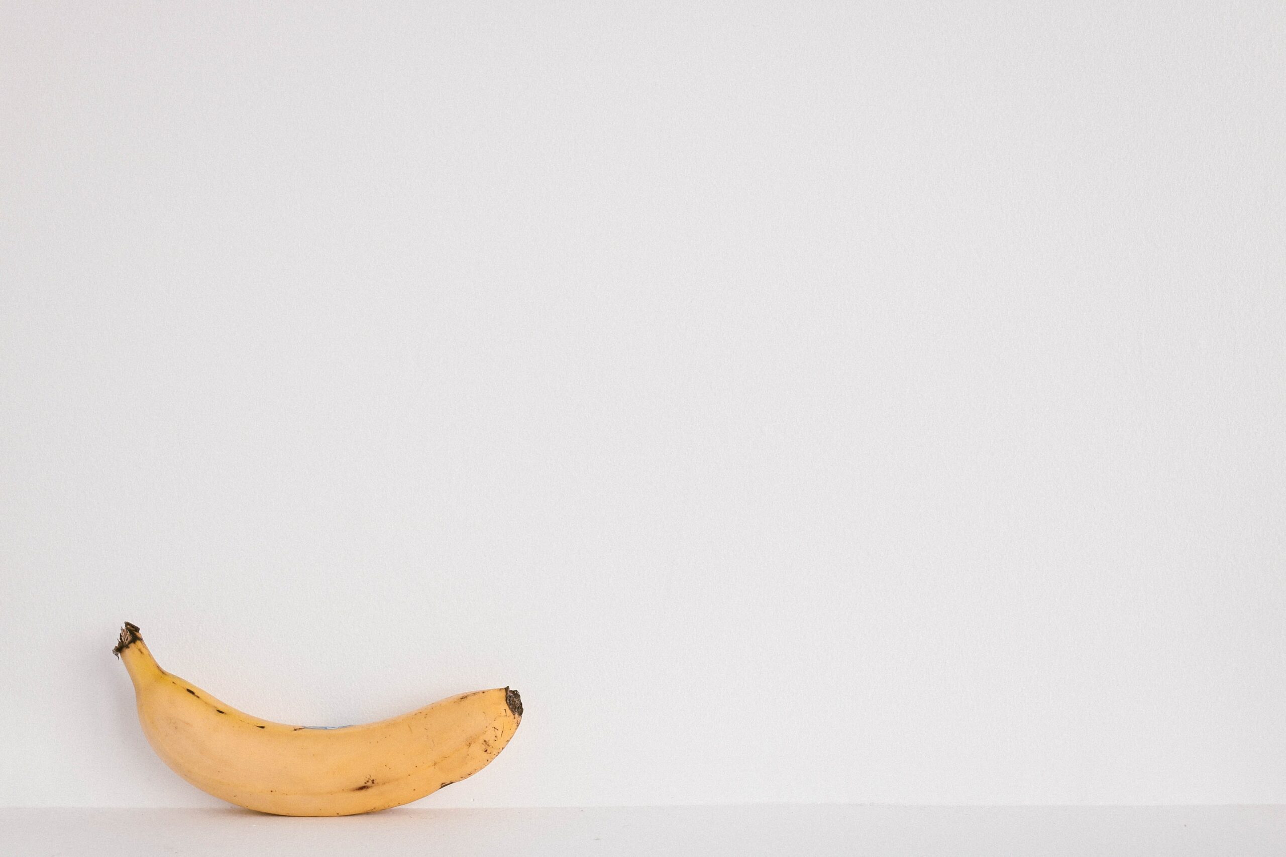 Eine Banane liegt auf einem Tisch vor einer weißen Wand