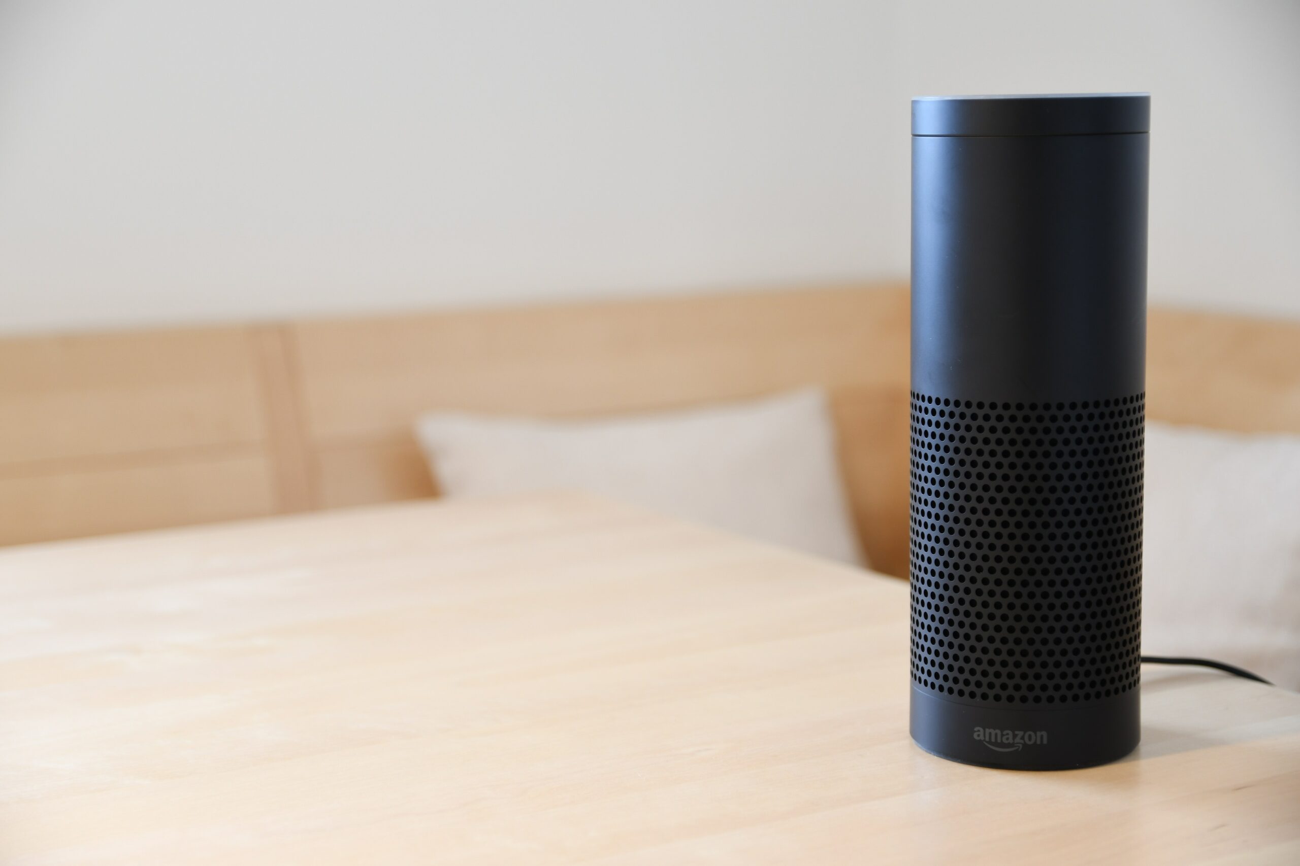 EIn Smart Home Speaker steht auf dem Tisch aus Holz