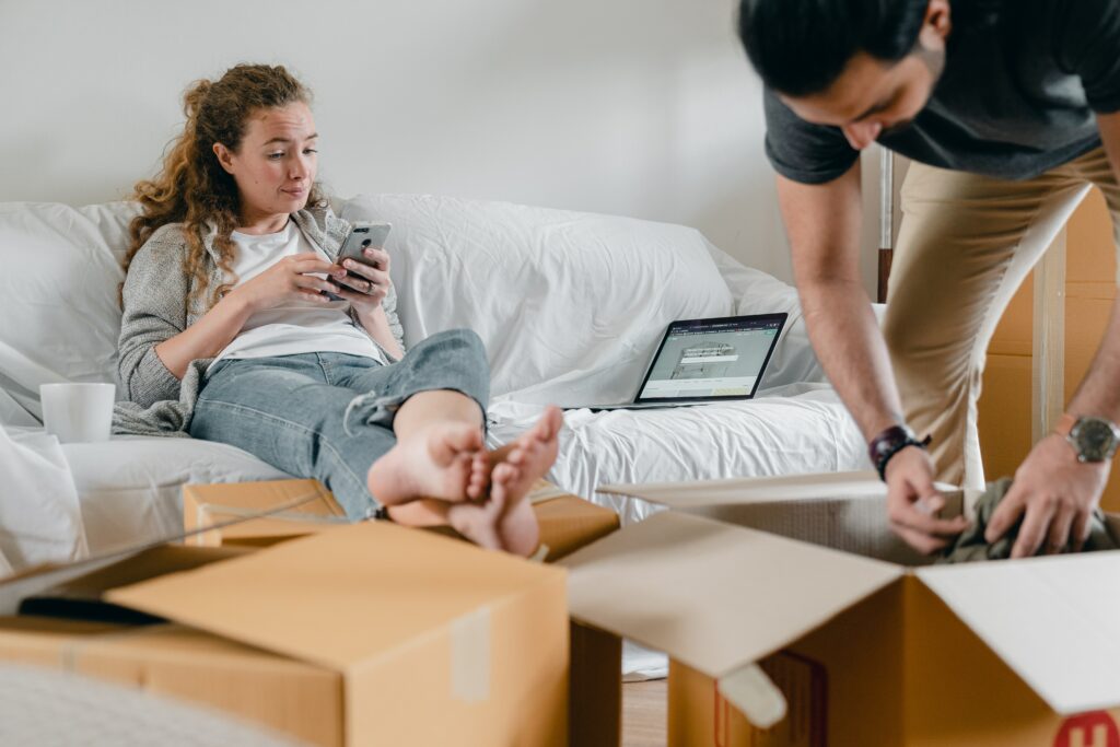 Junges Paar zieht in eine Wohnung und packt gerade die Umzugskartons aus.