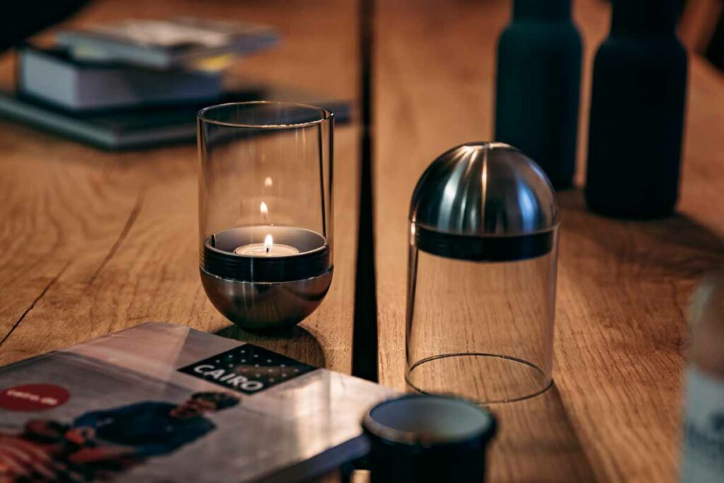 Zwei Höfats Gravity Candles steht auf einem Tisch. In einer der Gravity Candles brennt eine Kerze