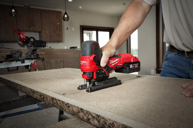 Eine Milwaukee Akku-Stichsäge sägt durch eine Holzplatte in einer Werkstatt