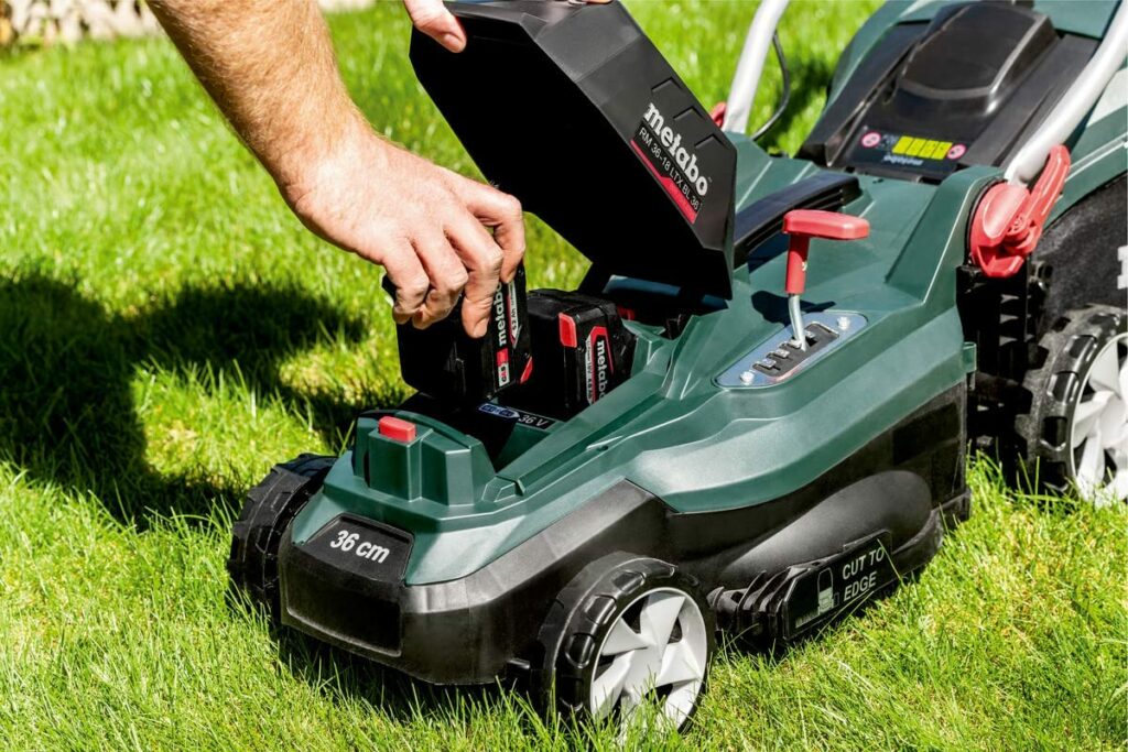 Eine Person wächselt den Akku beim Metabo RM 36-18 LTX BL 36 Akku-Rasenmäher welcher einer der besten Metabo Akku Gartengeräte ist