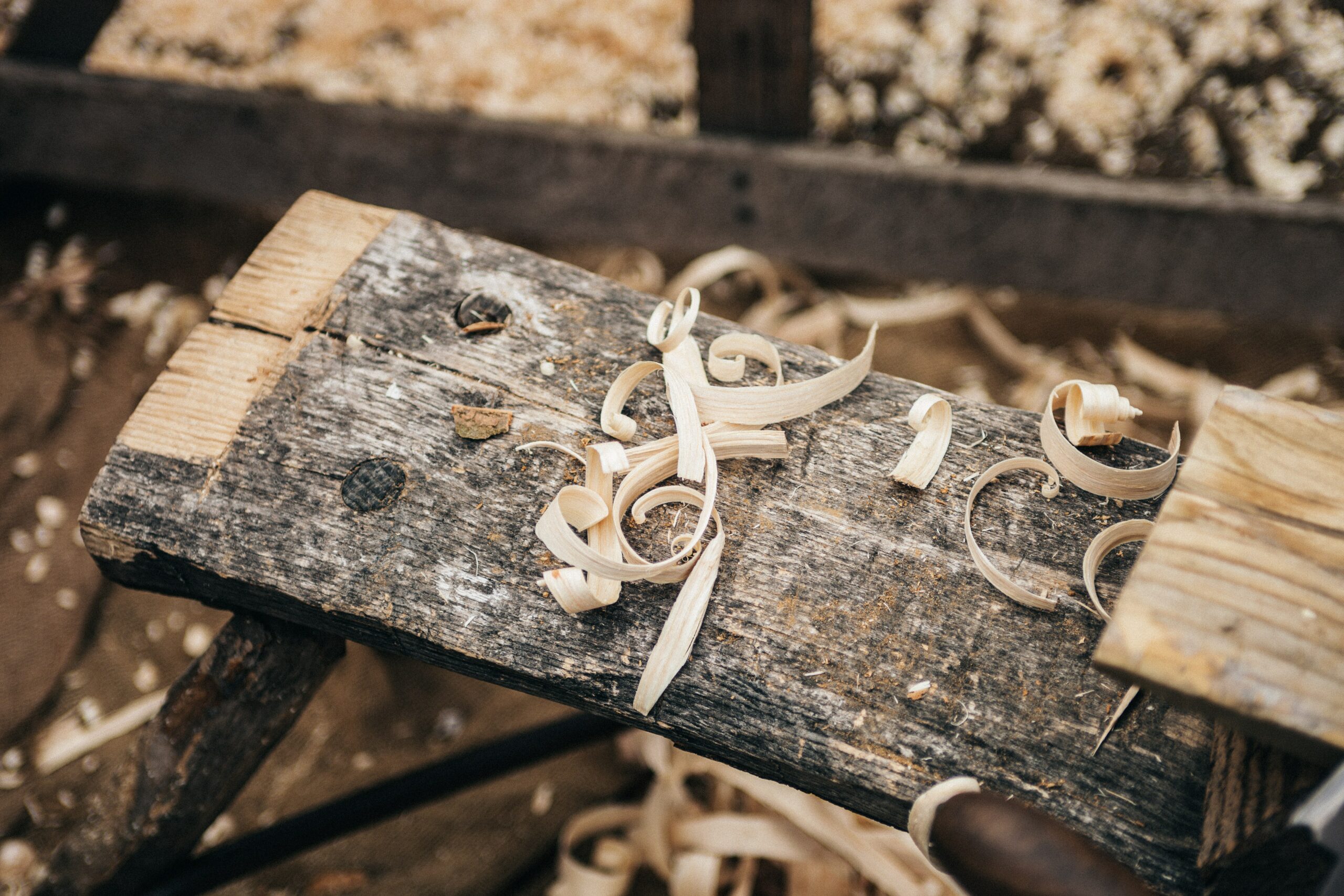 ein Holzbalken in einer Werkstatt auf dem Hobelspäne liegen