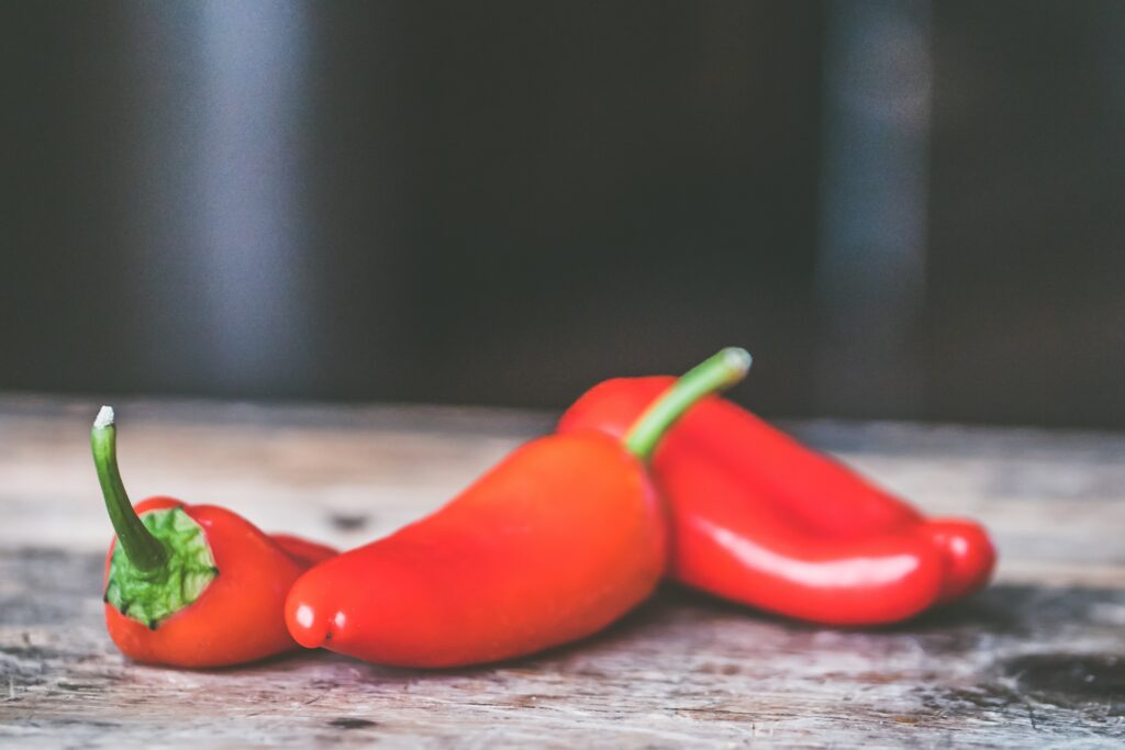 3 Chili Schoten auf einem Tisch. Chili-Anbau sind die perfekte Wahl für alle, die einen Schuss Geschmack und Farbe in ihren Garten oder auf ihre Terrasse bringen möchten