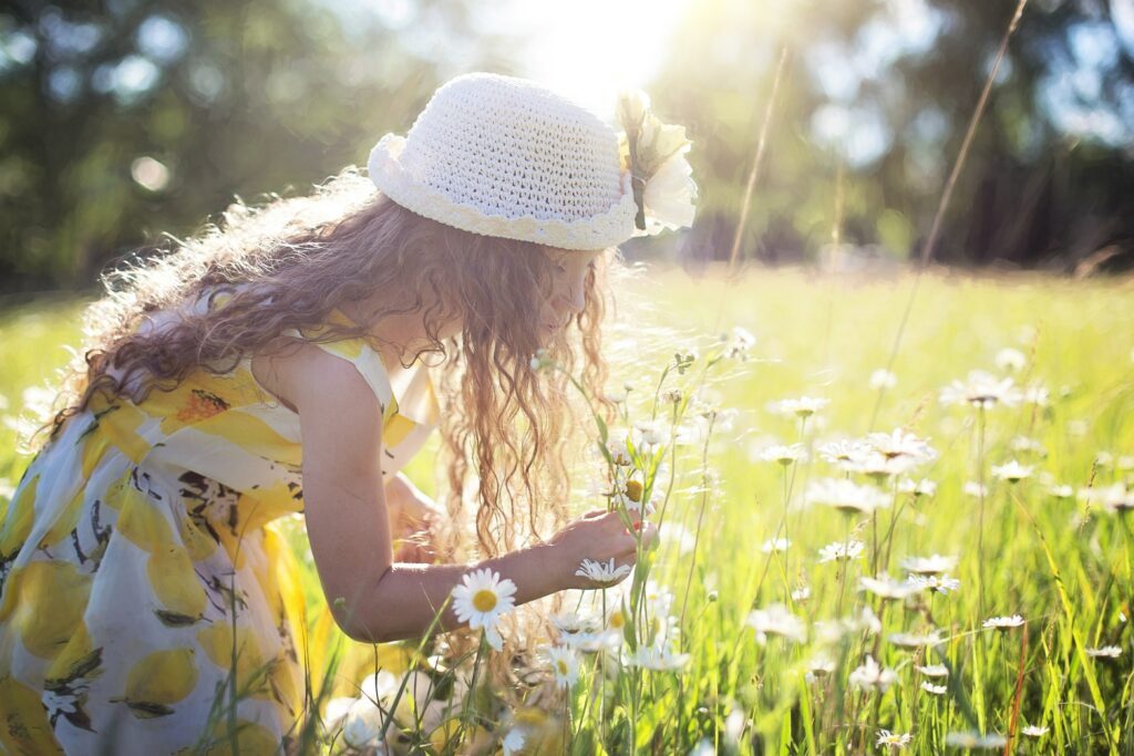 Ein Mädchen schaut sich ganz genau die Blüte eine Wildblume an und macht ihren Garten zum Abenteuerspielplatz