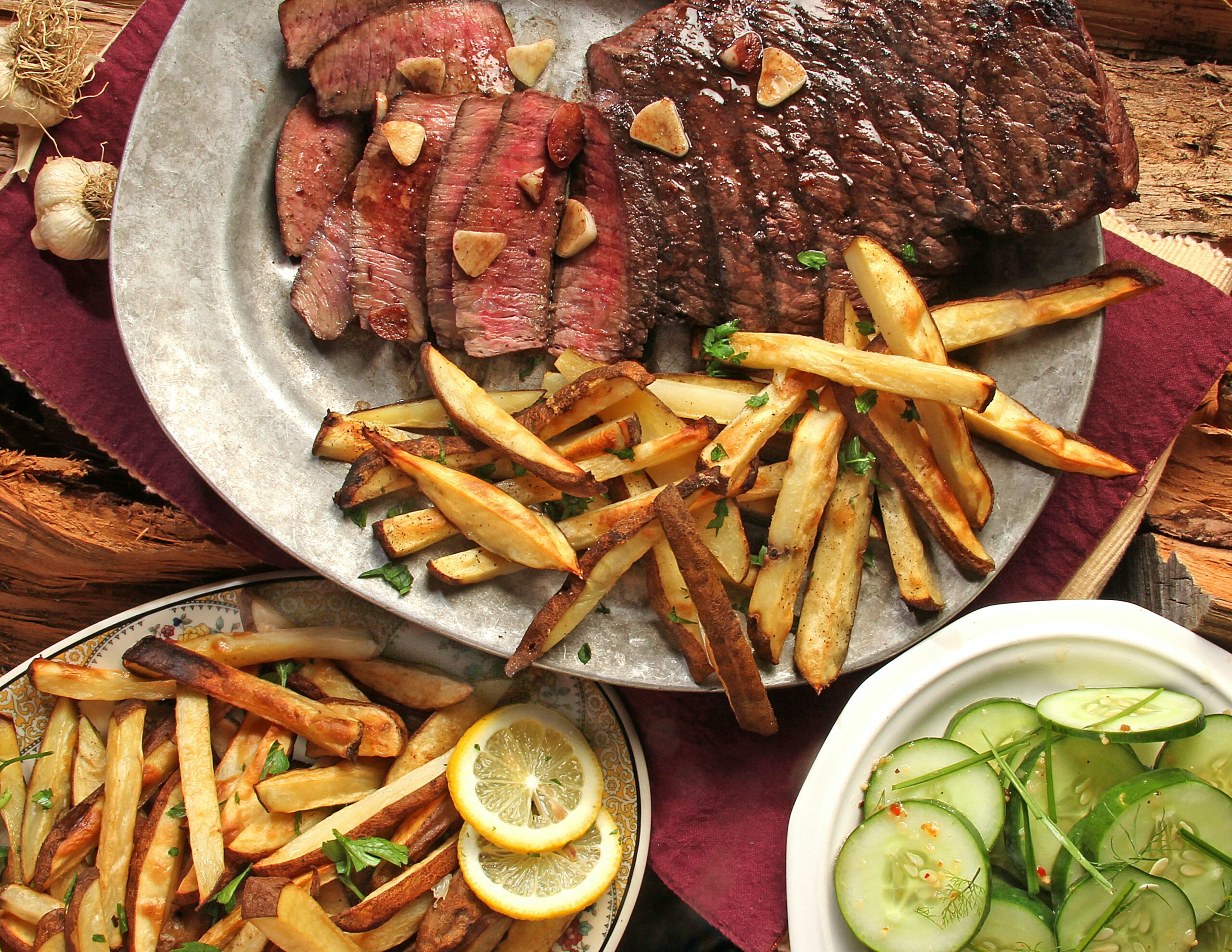 Ein Teller mit einem perfekt gegrilltem Steam und Pommes auf einem Holztisch für den perfekten grillabend
