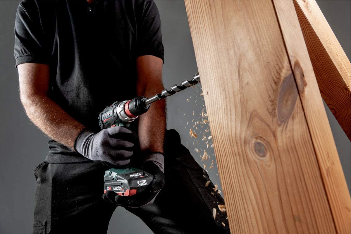 Ein Handwerker bohrt mit einem Metabo Akku Bohrer durch einen sehr dicken Balken