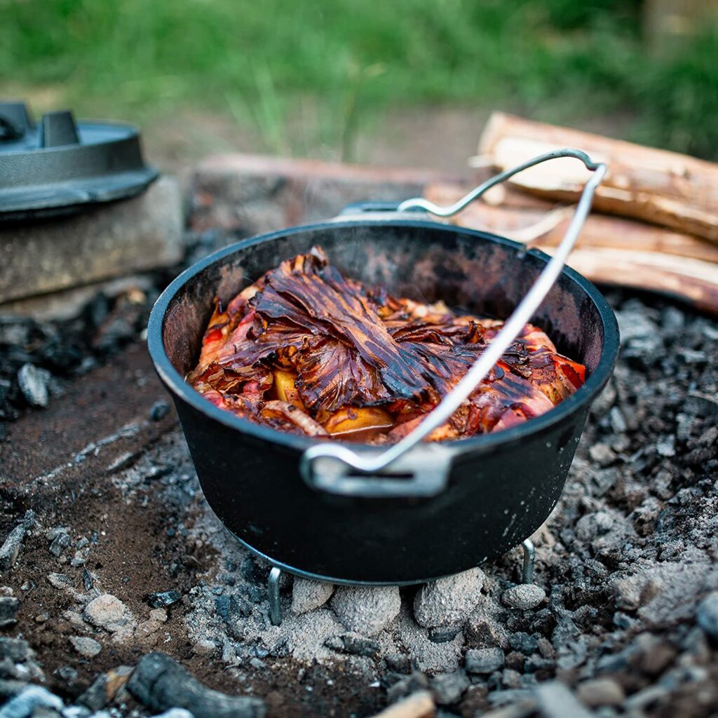 Der Dutch Oven von BBQ-Toro steht in der Glut eines Feuers mit geöffnetem Deckel