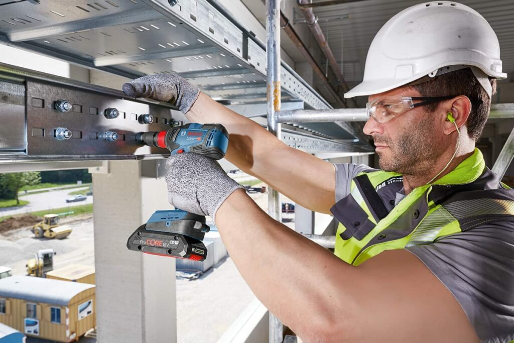 Ein Handwerker montiert mit einer Bosch Professional Akku Schlagbohrer einen Kabelschacht