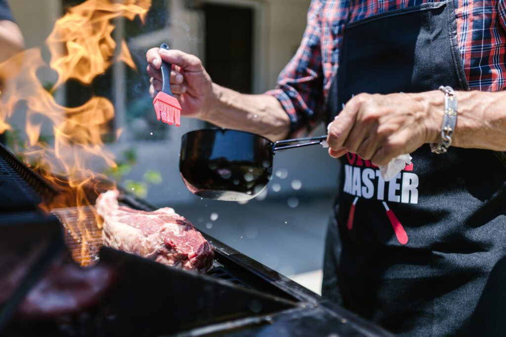 Perfekter Grillabend: Mann steht am Grill und bestreicht sein Grillgut mit Marinade