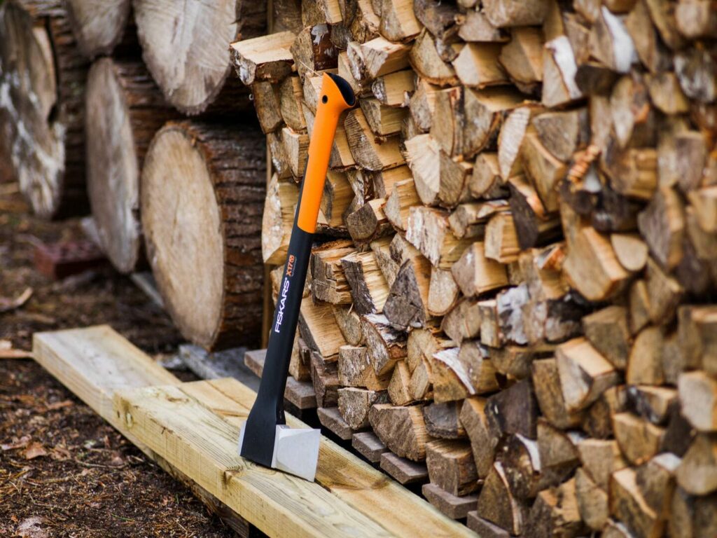 Eine Fiskars Spaltaxt lehnt gegen einen aufgeschichteten Stapel Brennholz