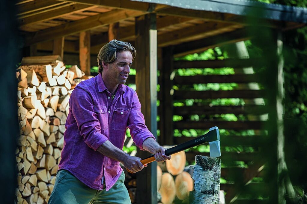 Ein Mann spaltet mit einer Fiskars Spaltaxt einen Holzstamm