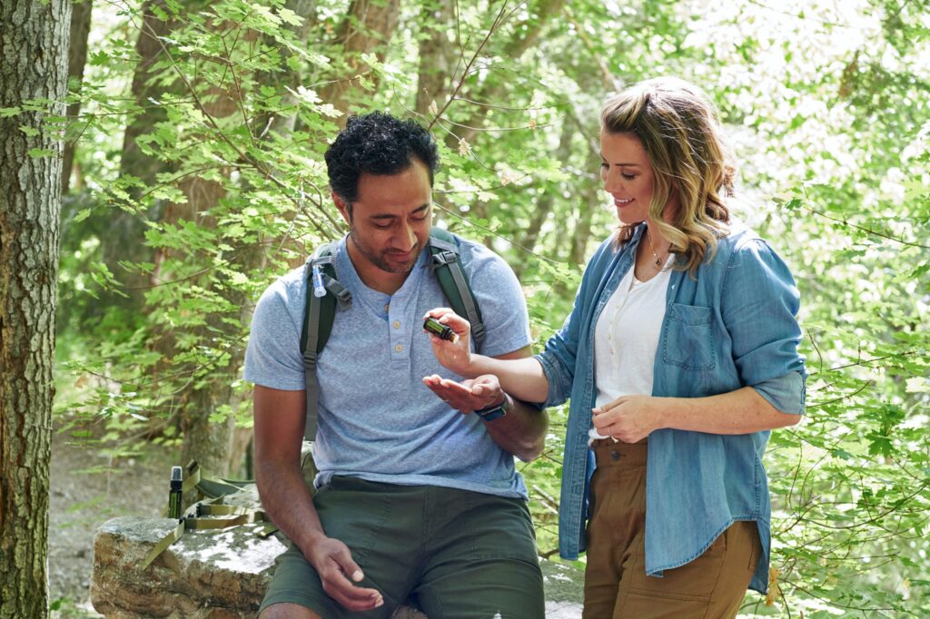 Zwei Personen beim wandern im Wald nutzen natürliche Mittel gegen Mückenstiche