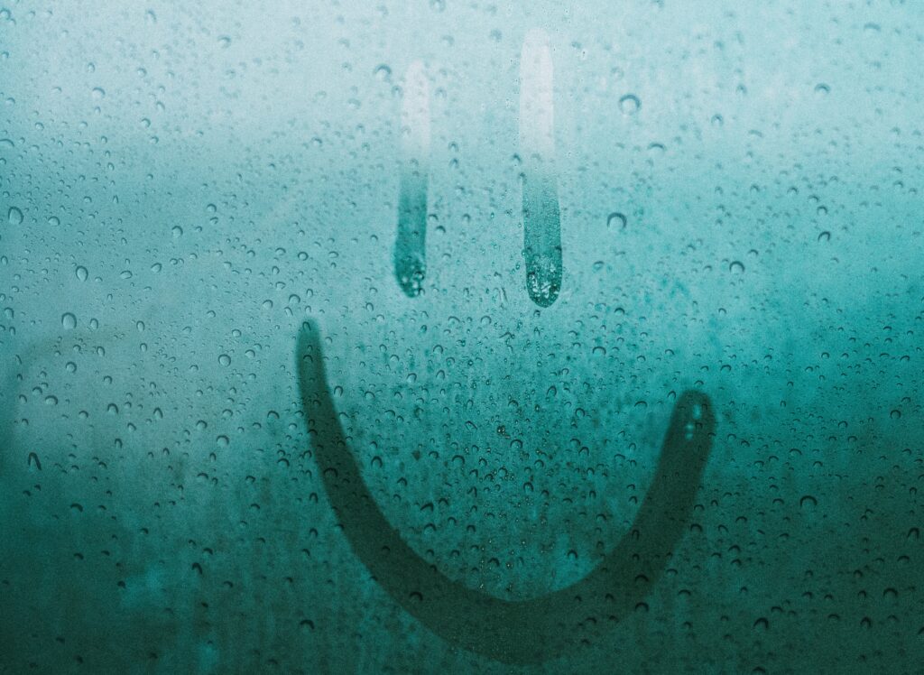 Ein Smiley wurde auf eine beschlagene Scheibe gemalt ein symbolbild für die entfernung von Luftfeuchtigkeit aus Räumen