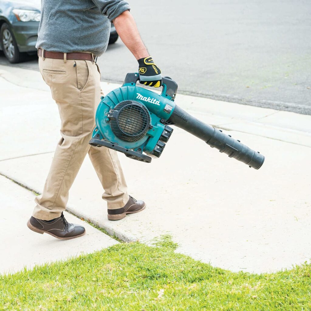 Ein Mann bläst mit dem Makita Akku Laubbläser seine Einfahrt des Hauses