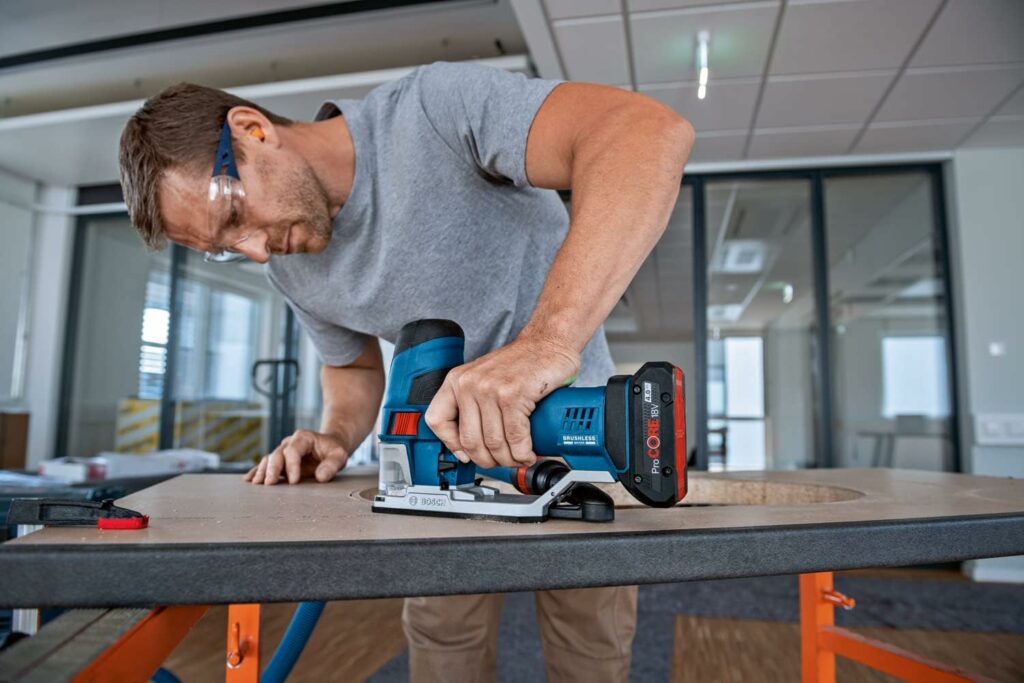 Bosch Professional 18V System Akku-Stichsäge GST 18V-155 SC wird von einem Handwerker dazu benutzt ein Holzbrett zu schneiden